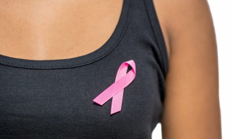 close up of african woman in t-shirt with breast cancer awareness ribbon over white background