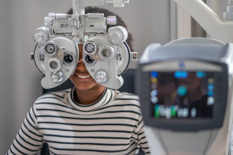 Close up Of african teen girl Doing Eye Test On Phoropter, African teen girl checking on her eye with optometry machine.